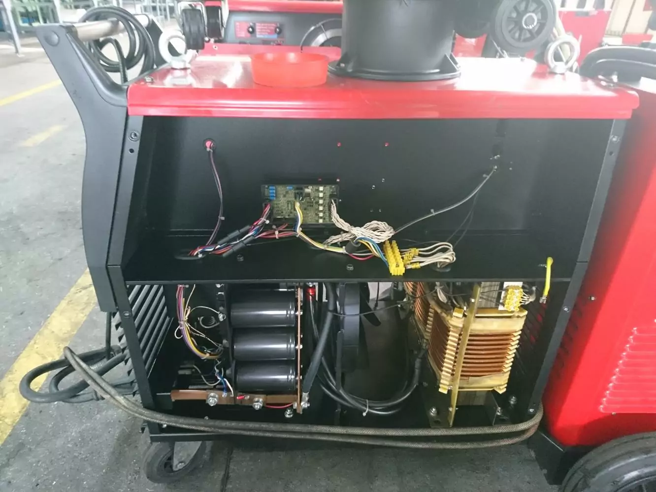 Czyszczenie spawalni i spawarek 3 Otwarta maszyna przemysłowa pokazuje wewnętrzne okablowanie, płytki drukowane i metalowe elementy, w tym cewki i cylindry, pod czerwoną obudową zewnętrzną. Wygląda na to, że przechodzi konserwację lub przegląd w warsztacie Galerii Zdjęć Czyszczenia Suchym Lodem.