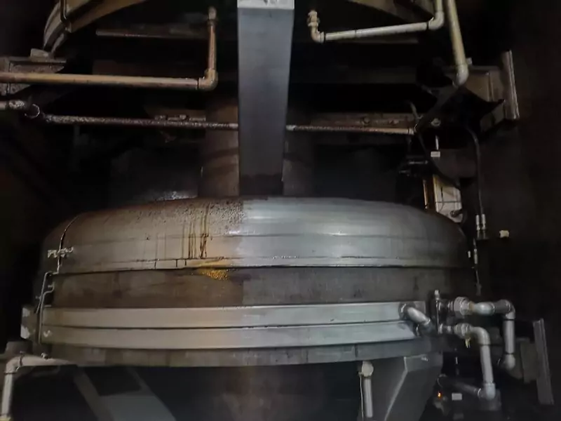 Przemysł spożywczy 5 Duży metalowy zbiornik przemysłowy z podłączonymi rurami i armaturą jest pokazany w słabo oświetlonym otoczeniu, z widocznymi plamami cieczy na powierzchni, co podkreśla potrzebę Czyszczenie Maszyn Spożywczych Suchym Lodem.