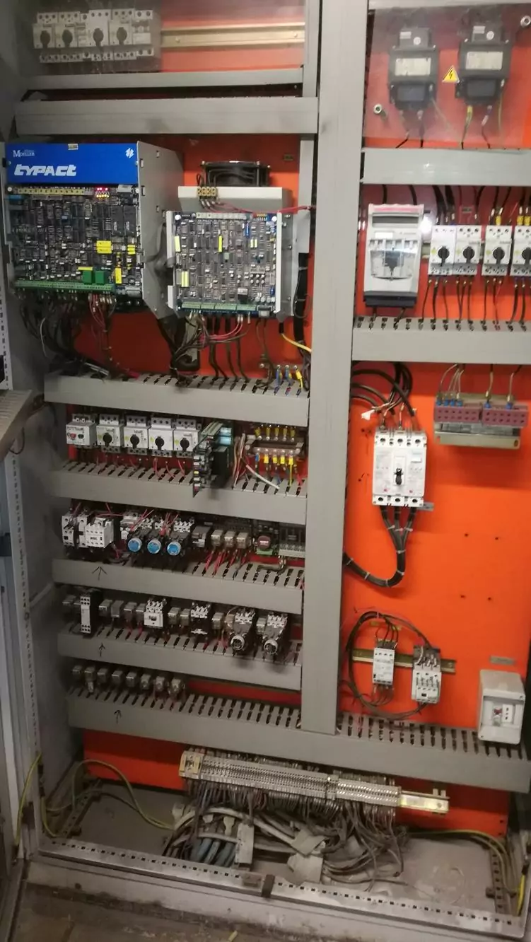 Czyszczenie instalacji i urządzeń elektrycznych 5 Otwarty panel sterowania elektrycznego z różnymi wyłącznikami, przekaźnikami, przewodami i przełącznikami jest starannie ułożony na pomarańczowym tle, ilustrując znaczenie Czyszczenia Rozdzielni Elektrycznych Suchym Lodem dla optymalnej konserwacji.