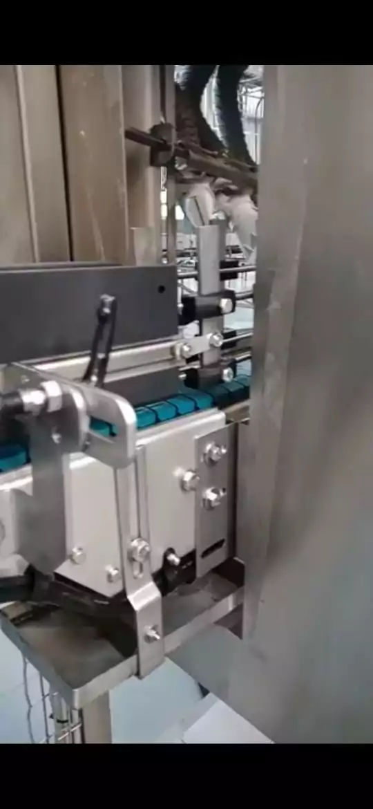 Przemysł spożywczy 6 Zbliżenie maszyny przemysłowej z niebieskim przenośnikiem taśmowym i metalowymi elementami, prawdopodobnie używanej do pakowania lub produkcji, podkreślające zalety Czyszczenia Maszyn Spożywczych Suchym Lodem w warunkach fabrycznych.